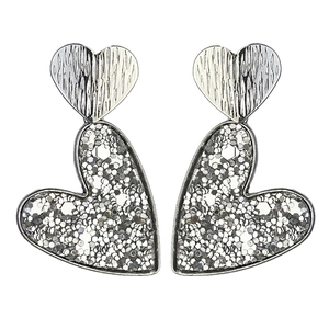Détail de boucles d'oreilles cœur argentées avec texture martelée et finition pailletée