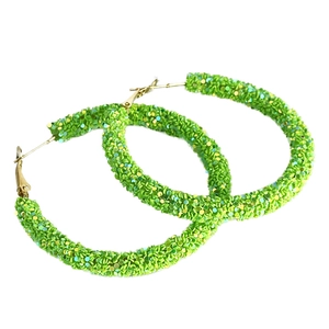 Detail of large green glitter hoop earrings with sparkling texture and gold hooks