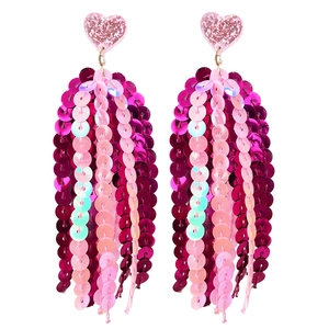 Détail macro de boucles d'oreilles cœur rose à paillettes avec pampilles brillantes