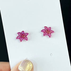 Dettaglio di orecchini a fiore rosa con glitter su cartoncino bianco da esposizione