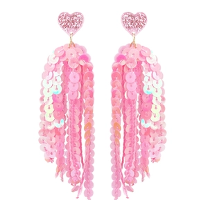 Gros plan de boucles d'oreilles cœur rose avec paillettes et franges irisées