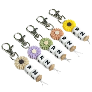 Close-up of nurse week keychains with sunflower beads and RN letters on white background