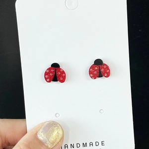 Dettaglio degli orecchini a lobo coccinella glitterati rossi fatti a mano su cartoncino