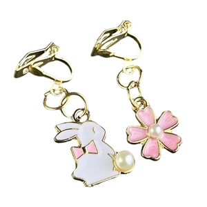 Detail of asymmetric clip-on earrings with white bunny, pink flower and pearls