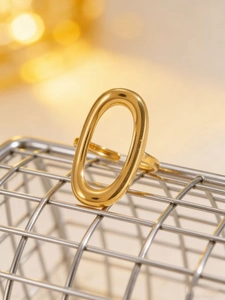 Macro detail van gouden ovale geometrische ring met gepolijste afwerking op een metalen rooster