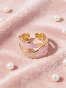 Detail of gold-plated wavy double-layer ring with pink enamel on soft velvet backdrop