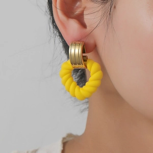 Detail of trendy gold U-shaped metal buckle with bright yellow twisted hoop earring