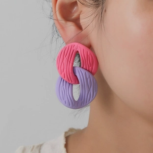 Detail of pink and purple interlocking resin earrings with a wavy textured surface