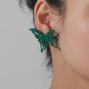 Detail of a dark green butterfly earring with hollow wings and matte metal finish