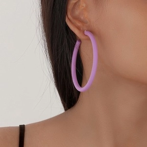 Close-up of a model wearing large purple matte drop earrings with hollow geometric design