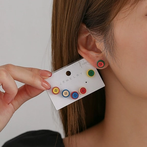 Dettaglio di orecchini colorati a forma di bottone su una modella e scheda gioielli