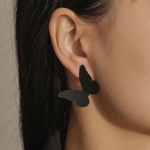 Close-up of minimalist black matte butterfly earrings on a model showing fine texture