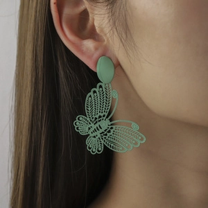 Detail of matte bean green butterfly drop earrings with intricate hollow-out texture