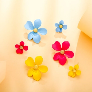 Detailed macro of vibrant floral earrings in blue, rose, and yellow with gold centers