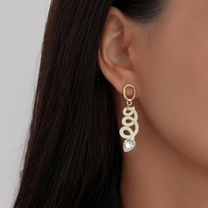 Close-up of golden spiral earrings with a sparkling water-drop crystal on a model