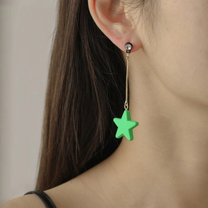 Model wearing green star drop earrings with long gold chains and white rhinestones