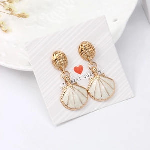 Elegant gold shell drop earrings with white enamel on a stylish gift display card