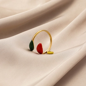 Détail d'une bague ajustable en acier doré avec des gouttes d'émail colorées sur satin
