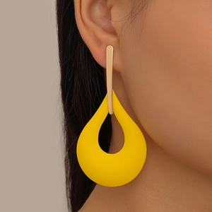 Close-up of stylish oversized hollow teardrop earrings in bright yellow matte finish
