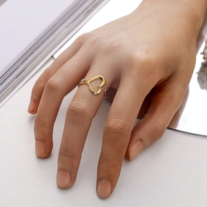 Detailed view of a gold hollow heart ring on a finger with an open adjustable band