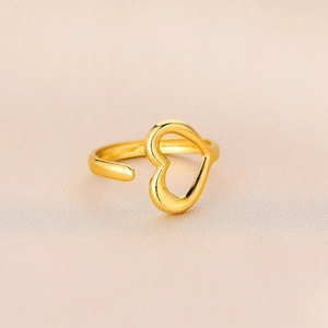 Macro detail of gold-plated hollow heart ring on beige silk fabric background