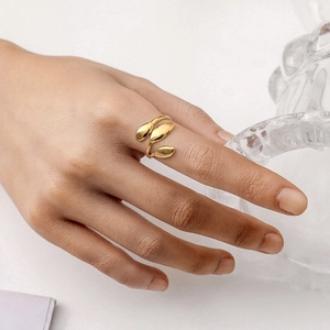 Gros plan d'une bague feuille plaquée or avec ouverture réglable portée au doigt