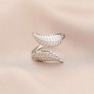 Macro shot of silver-tone leaf ring showing detailed textures on satin background