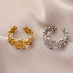 Macro detail of gold and silver floral open rings on soft champagne silk fabric