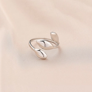 Détail d'une bague ajustable en argent en forme de feuille sur tissu de soie rose