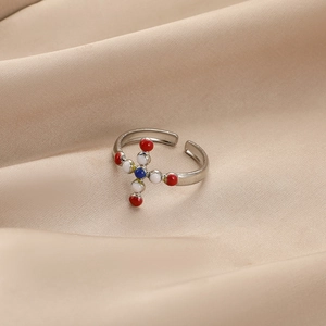Bague ajustable en argent avec croix perlée colorée sur fond de satin élégant