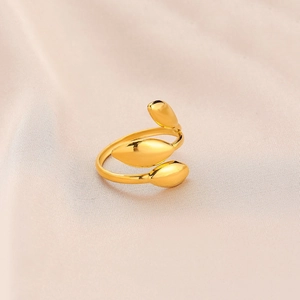 Gros plan d'une bague ouverte dorée en forme de feuille sur soie beige luxueuse