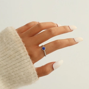 Gros plan d'une bague feuille en argent avec une pierre bleue ronde au doigt