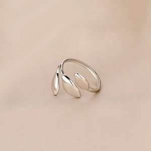 Détail macro de bague feuille argentée ajustable sur fond de satin champagne élégant