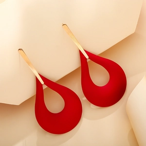 Detail of red hollow teardrop earrings with matte finish and gold metallic accents
