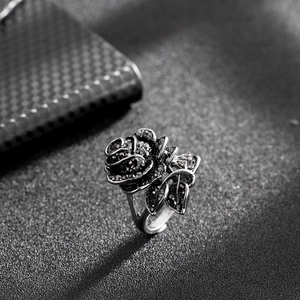 Détail macro d'une bague rose noire gothique sertie de cristaux sur fond texturé noir