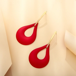 Close-up of matte red teardrop hollow earrings with gold metal stud on cream background