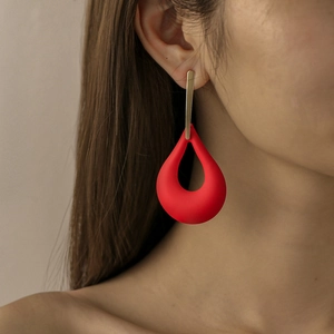 Close-up of red matte waterdrop hollow earrings on model showing fashion metal texture