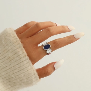 Détail de la bague ovale en émail coloré montrant le design bleu et blanc sur le doigt