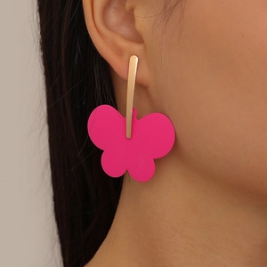 Detail shot of oversized pink butterfly drop earrings with golden polished metal bars