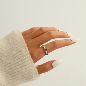 Gros plan d'une bague chaîne en émail coloré au doigt avec fond de pull en maille douce
