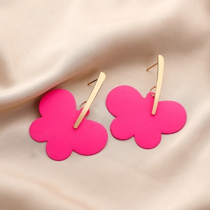 Macro shot of bright pink floral lacquer earrings on elegant champagne silk fabric