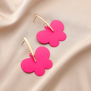 Detail view of pink matte paint butterfly drop earrings on champagne satin fabric background