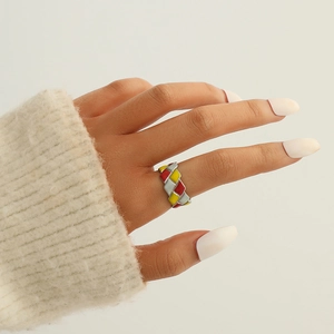 Gros plan d'une large bague en émail coloré avec motif tressé en diagonale sur une main