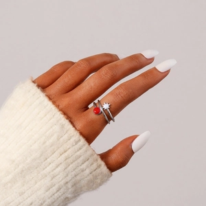 Détail d'une bague double en acier inoxydable avec perle rouge et étoile blanche au doigt