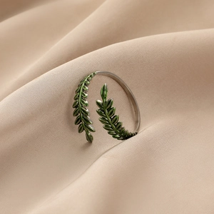 Gros plan d'une bague feuille réglable en argent avec émail vert sur tissu en soie
