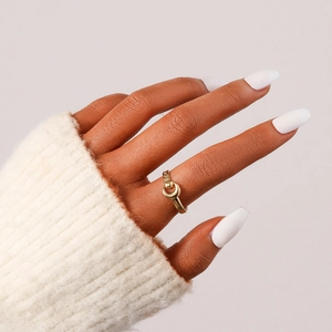 Detailed view of an elegant gold crescent hollow ring worn on finger with knit sweater