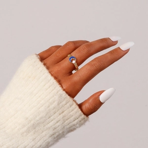 Close-up of golden crescent ring with blue inlay and bead on finger with knit sweater