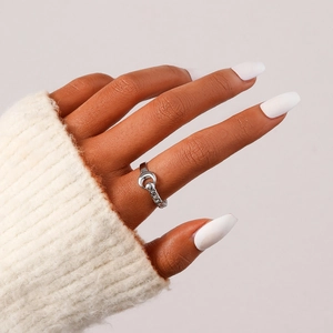 Close-up of a silver crescent moon and thick chain ring on a woman's index finger