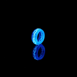 Vue détaillée de la bague aux motifs de ronces lumineuses bleues dans l'obscurité