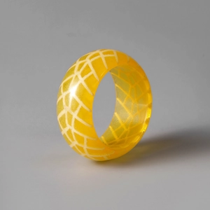 Detailansicht eines gelben Harzrings mit weißem geometrischem Crackle-Muster